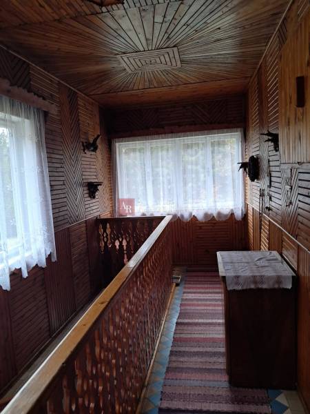 A wooden interior of a family house with decorative railings and carpets in the hallway.
