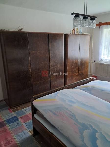 A bedroom in a family house with a bed, wardrobes, and a carpet with a colorful pattern.