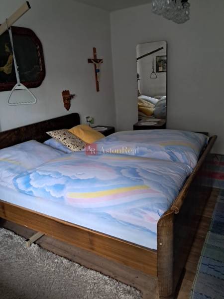 Bedroom in a family house with wooden decor, a large mirror, and wall decorations.