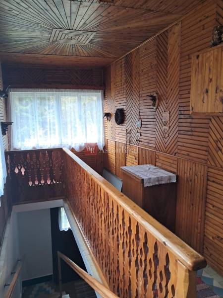 A hallway in a family house with wooden paneling and carved railing.