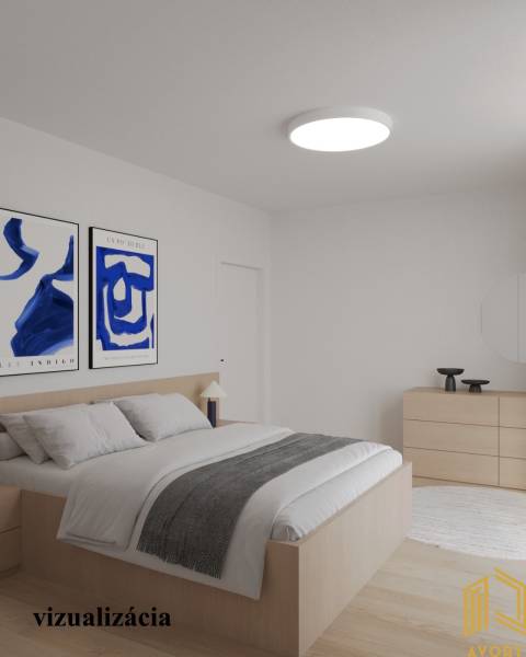 A bright bedroom in a two-room apartment with wooden floor decor and paintings on the wall.