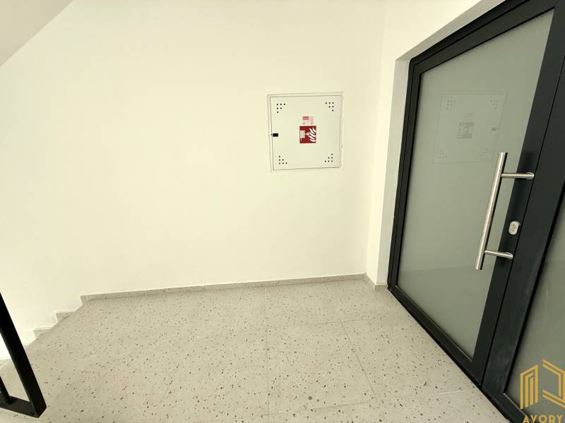 A hallway with glass doors, white walls, and a floor with a white decor in a 2-room apartment.