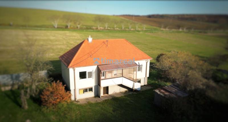 A family house in Dobrá Voda with a sloped roof, surrounded by greenery and meadows.