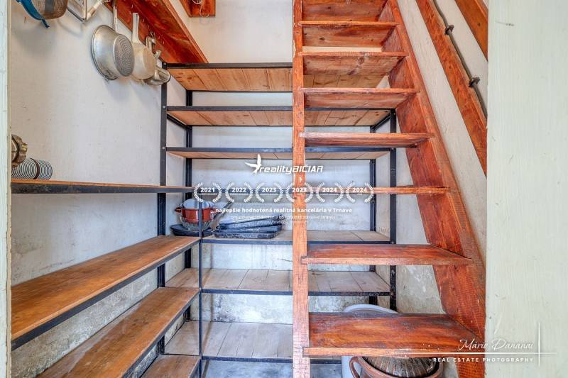 Storage space under the stairs with shelves and kitchen equipment in a family house.