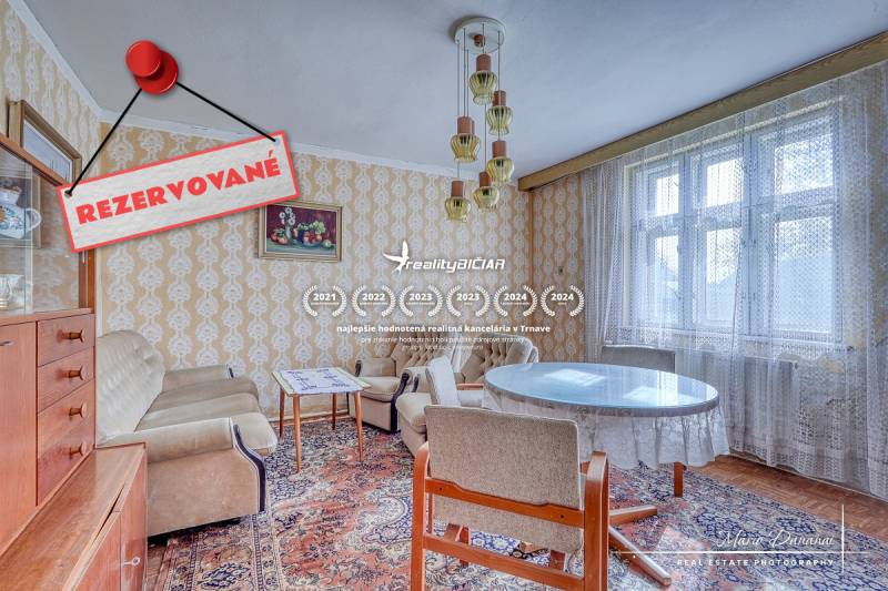 Interior of a family house with vintage furniture, wallpaper, and a large window with a lace curtain.