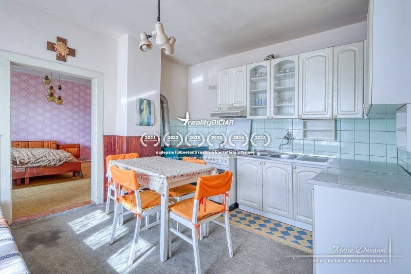A kitchen in a family house with a dining table and a view into the bedroom.