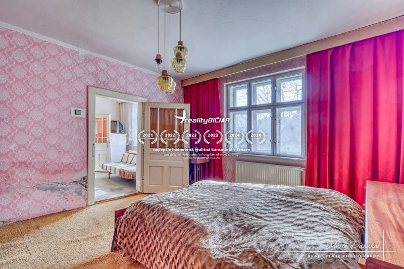 A bedroom in a family house with pink wallpaper and red curtains.