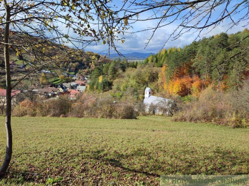 A church surrounded by autumn nature in Záhrady, Hlboké nad Váhom with a view of the mountains.