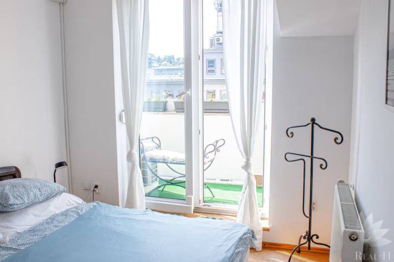 A bedroom in a 3-room apartment with a balcony and a view of the exterior through a French window.