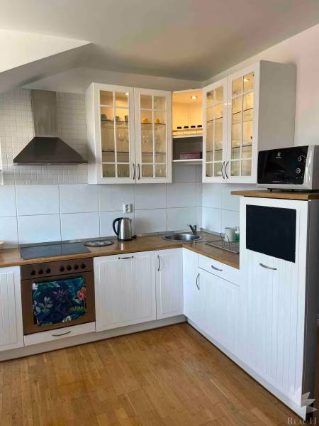 A kitchen in a 3-room apartment with wooden flooring, white cabinets, and storage space.