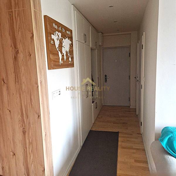 A hallway in a 2-room apartment with a wooden decor floor and storage spaces.