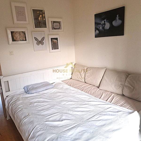 A bedroom in a 2-room apartment with a sofa, bed, and paintings on the wall.
