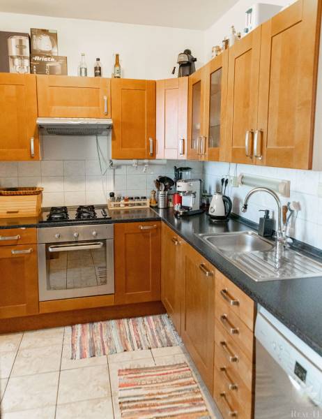 A kitchen in a 2-room apartment with brown cabinets, a stove, and a dishwasher.