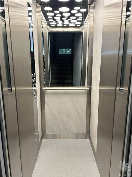 Interior of an elevator with lighting and stainless steel walls.