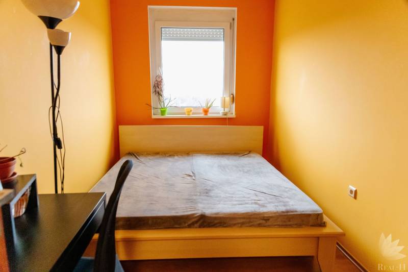 Bedroom with a bed, desk, and window in a 2-room apartment.