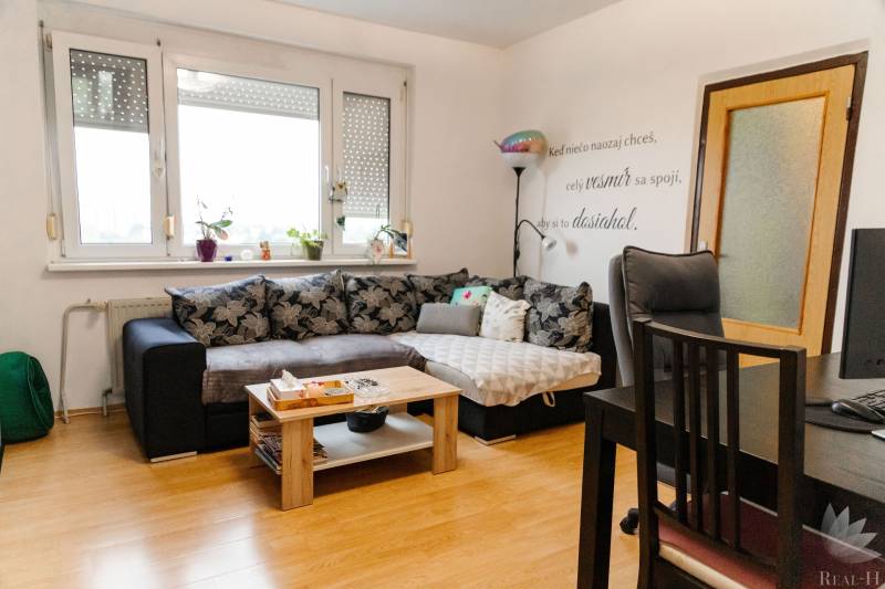 Living room in a two-room apartment with a corner sofa and a floor with a wooden decor.
