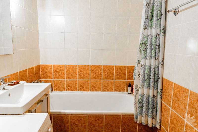 A bathroom with a bathtub and ceramic tiles in a 2-room apartment.