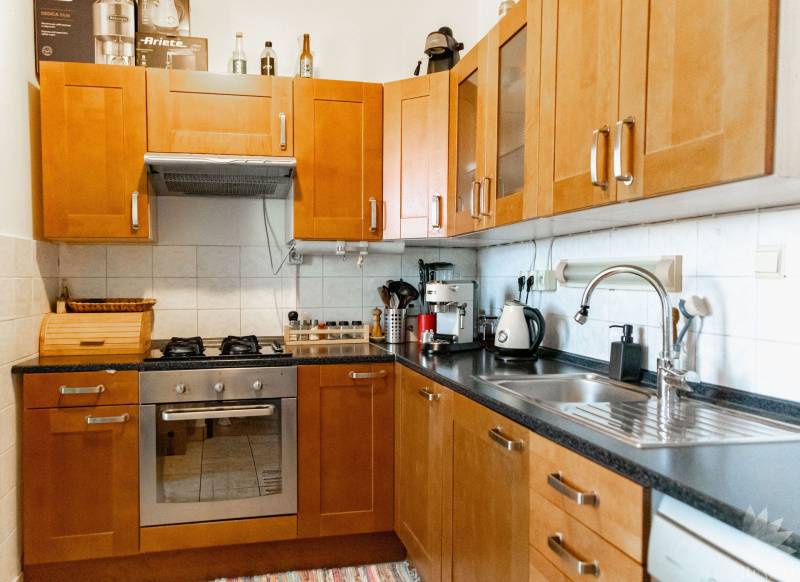 A kitchen with wooden cabinets and appliances in a 2-room apartment.