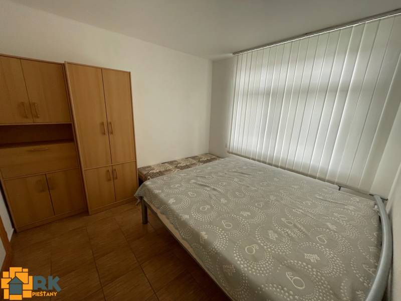 Bedroom in a family house with white blinds, bed, and wardrobes.