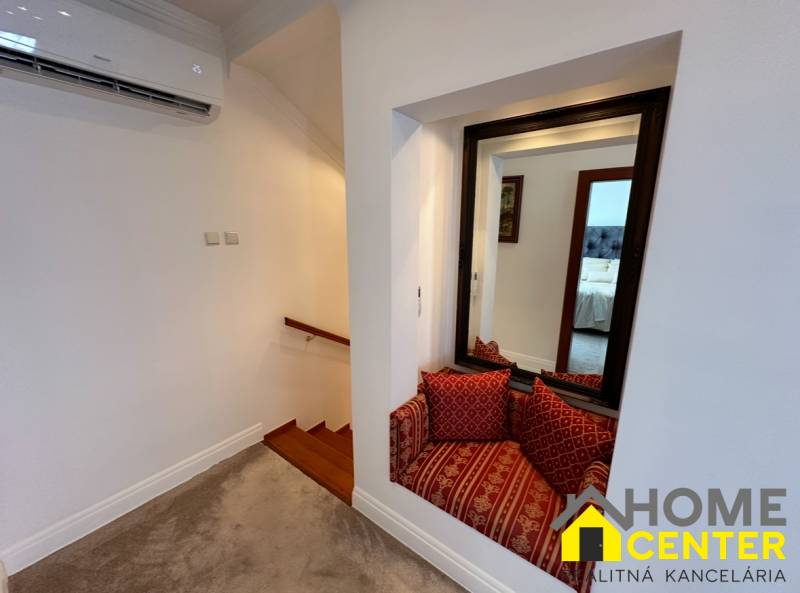 A family house features stairs with a wooden decor, a mirror, and a seating nook with cushions.