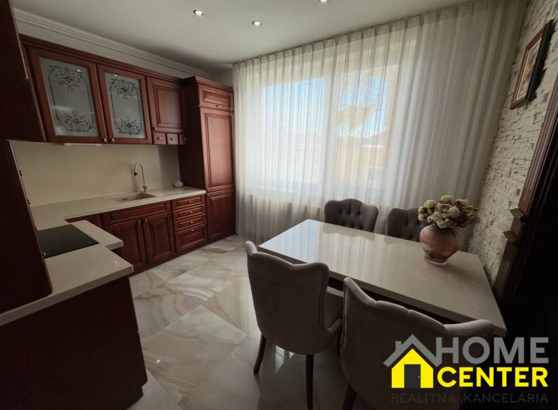 A kitchen with dark cabinets, white curtains, and floral decoration in a family house.