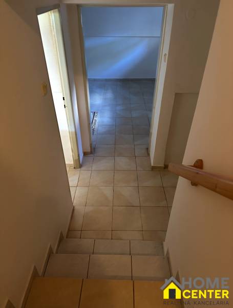 A hallway with tiles leads to a room in a family house with a tiled floor.