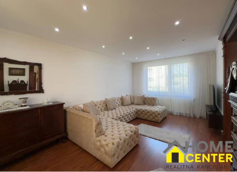 Living room with a large sofa, wooden decor flooring, and antique furniture.