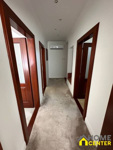 A hallway in a family house with white walls, carpet, and wooden door frames.