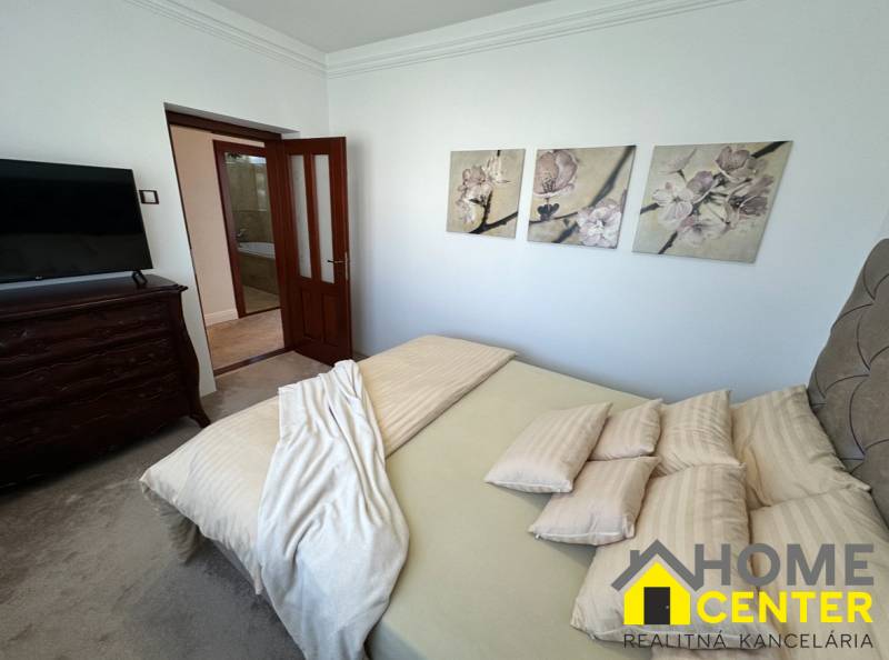 Bedroom of a family house with decorative paintings on the wall, upholstered furniture, and doors.