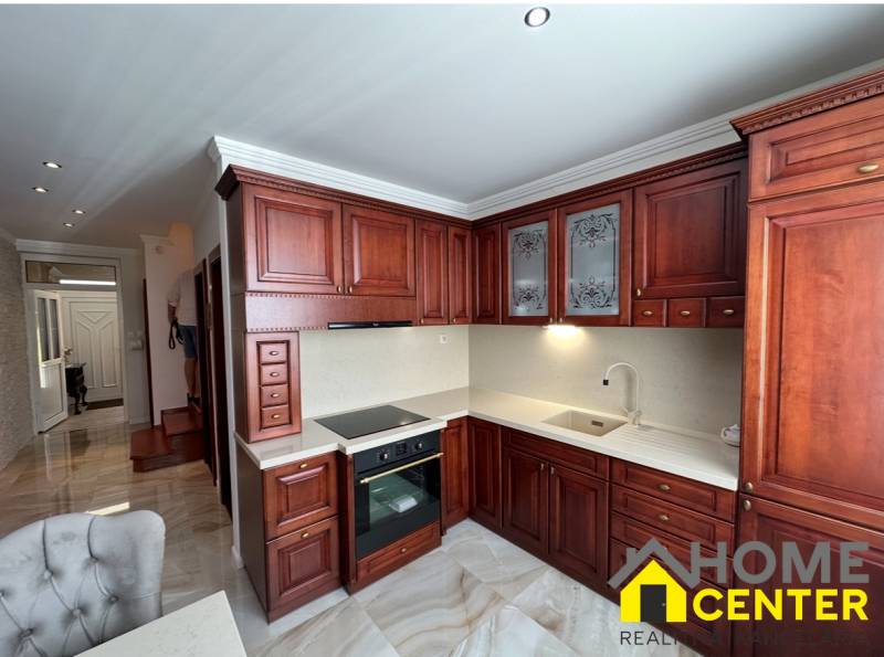 A kitchen with dark wooden cabinets and a wooden decor floor in a family house.