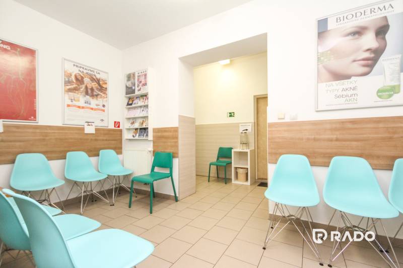A waiting room with turquoise chairs, walls with wooden decor, medical posters on the walls.