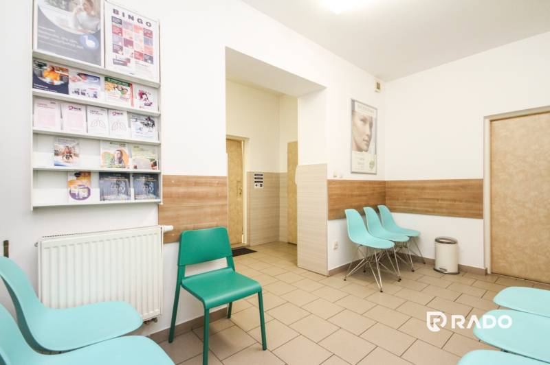 A waiting room with turquoise chairs and magazines, equipped with a wooden decor floor.