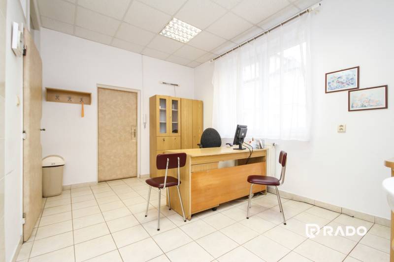 An office with wooden furniture, a computer, and decorations on the walls, tiled floor.