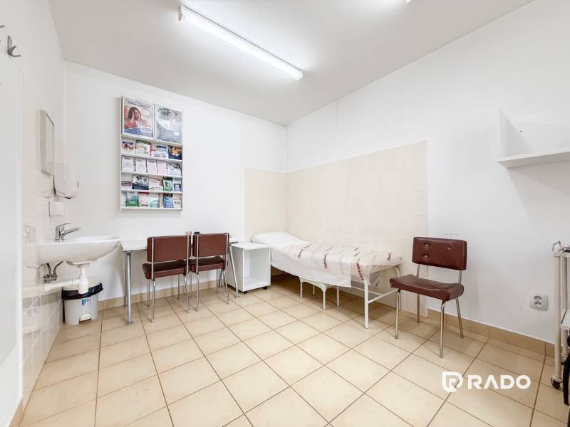 A room in the office with tiles, a sink, chairs, and a couch.