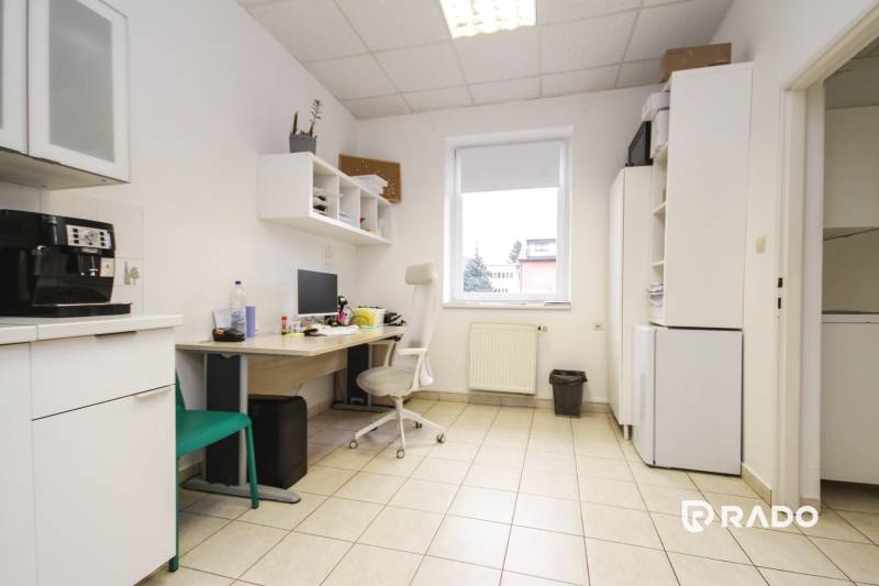 An office with tiles, a space with a computer, furniture, and a coffee maker.