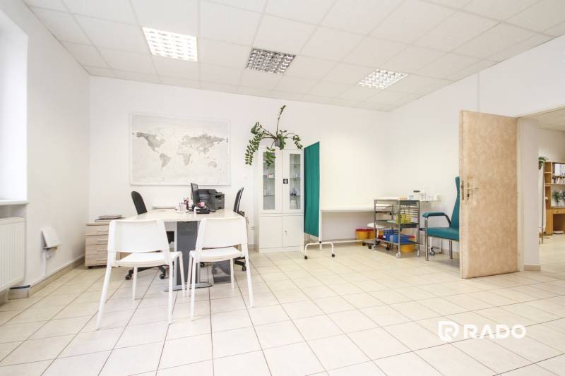 Office with white furniture, world map, green wall, sanitary equipment, and a plant.