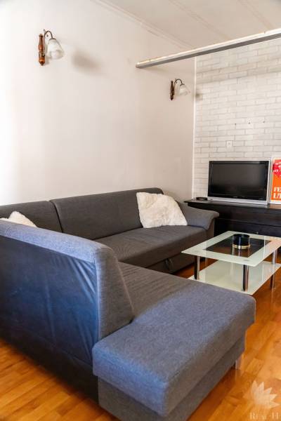 Living room in a 2-room apartment with a corner-arranged sofa and a television.