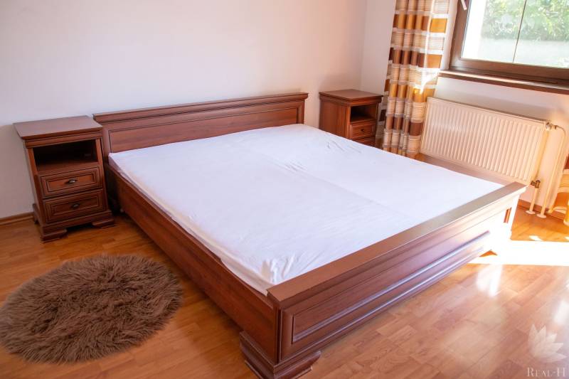 Bedroom with a wooden bed, nightstands, and a floor with a wooden decor in a 2-room apartment.