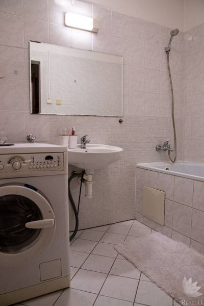 Bathroom in a 2-room apartment with a bathtub, washing machine, and sink.