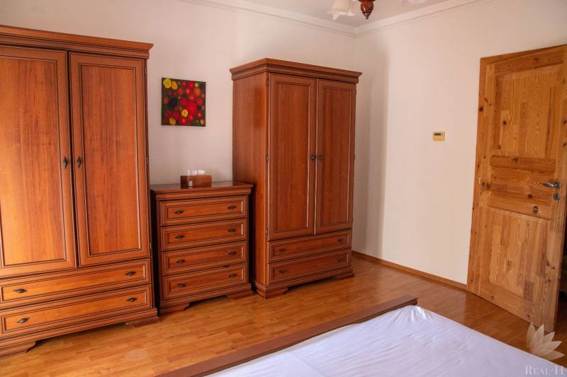 A bedroom with wood-patterned flooring, wardrobes, and a dresser in a two-room apartment.