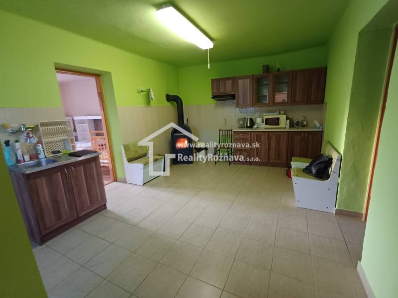 A kitchen in a family house with wooden decor, green walls, wood-burning stove.