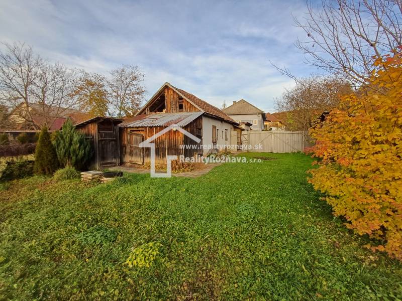 A family house in Dlhá Ves with a garden, wooden extensions, and autumn vegetation.