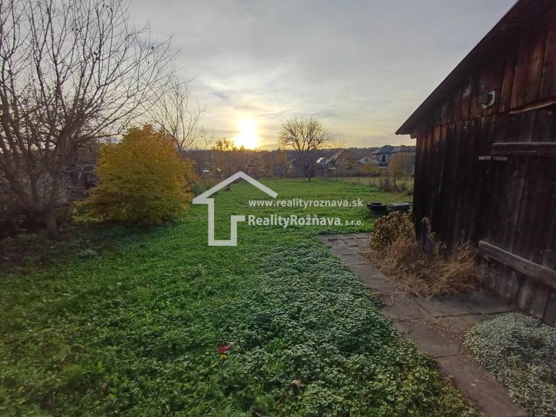 A garden by a family house in Dlhá Ves with a grassy plot and an old wooden structure.