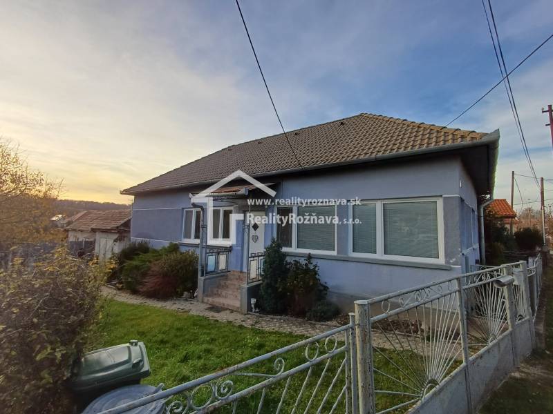 A family house in Dlhá Ves, blue facade, sloped roof, front garden, metal fence.