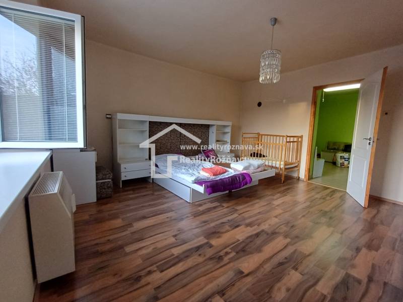 Children's room in a family house with a bed, crib, and floor with wooden decor.