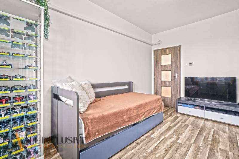 A room in a 3-room apartment with a car cabinet, a sofa, and a floor with a wooden decor.