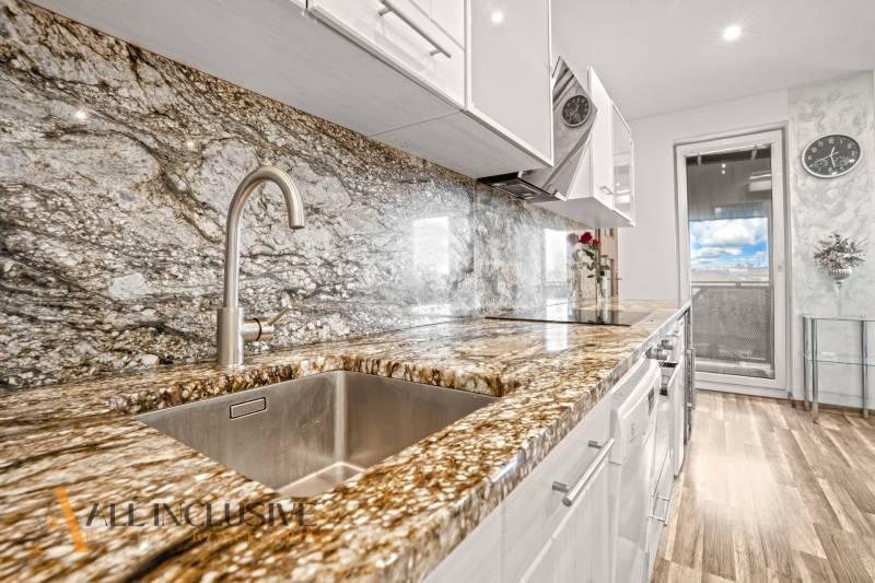 A kitchen with a stone countertop and a wooden decor floor in a 3-room apartment.
