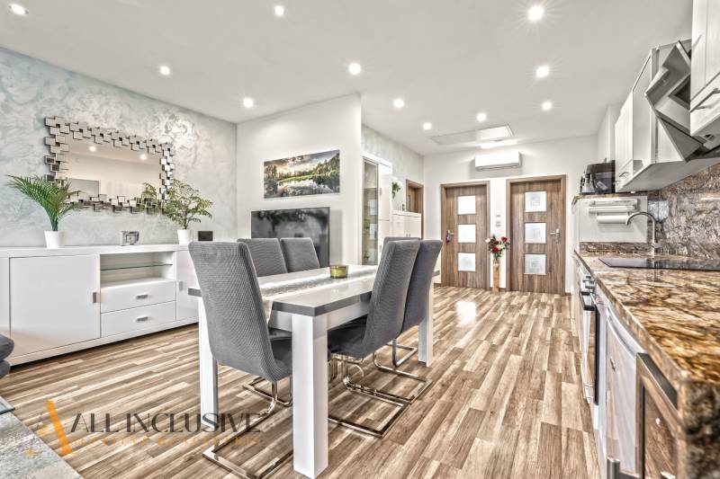 Dining area in a 3-room apartment with a wooden decor floor and a stylish mirror.