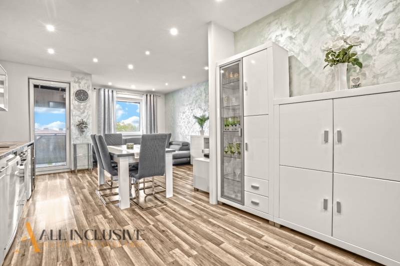 A bright interior of a 3-room apartment with a wooden decor floor and white furniture.