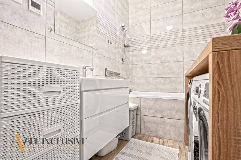 Bathroom in a 3-room apartment with a bathtub, tiles, and a floor with a wooden decor.